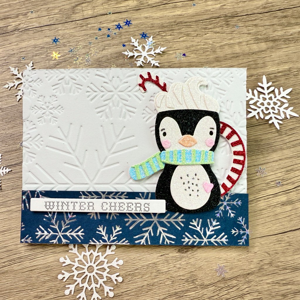 A festive card featuring a cute penguin with a scarf and a candy cane, surrounded by embossed snowflakes and a 'Winter Cheers' sentiment.