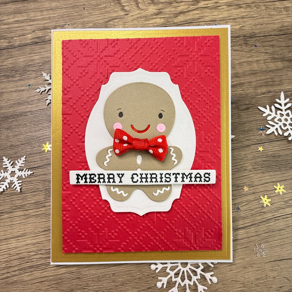 A festive Christmas card featuring a gingerbread man with a red polka dot bow tie, set against an embossed red background, and a gold border. The card is adorned with the text 'MERRY CHRISTMAS.'