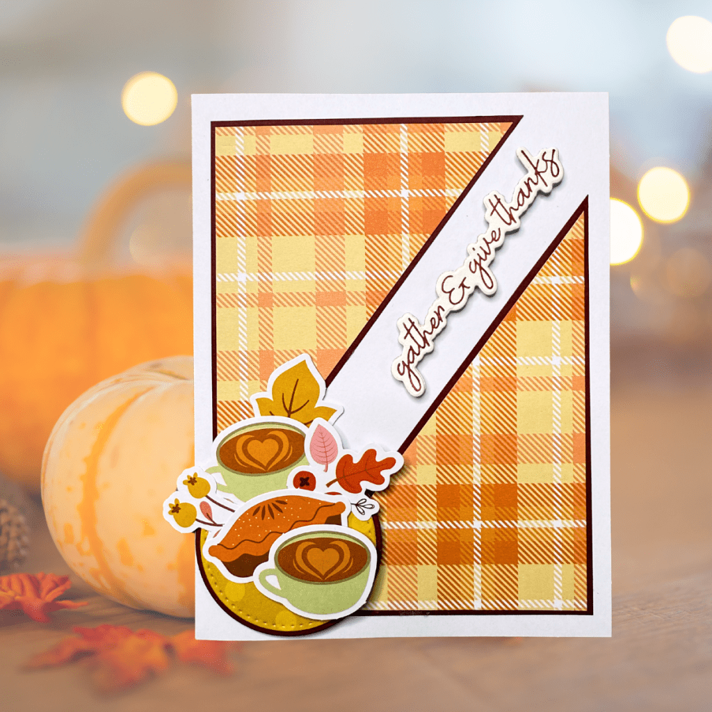 A handmade card featuring a yellow plaid background with a sentiment that says 'gather & give thanks'. The card includes layered decorative elements like coffee cups, a slice of pie, and colorful leaves.