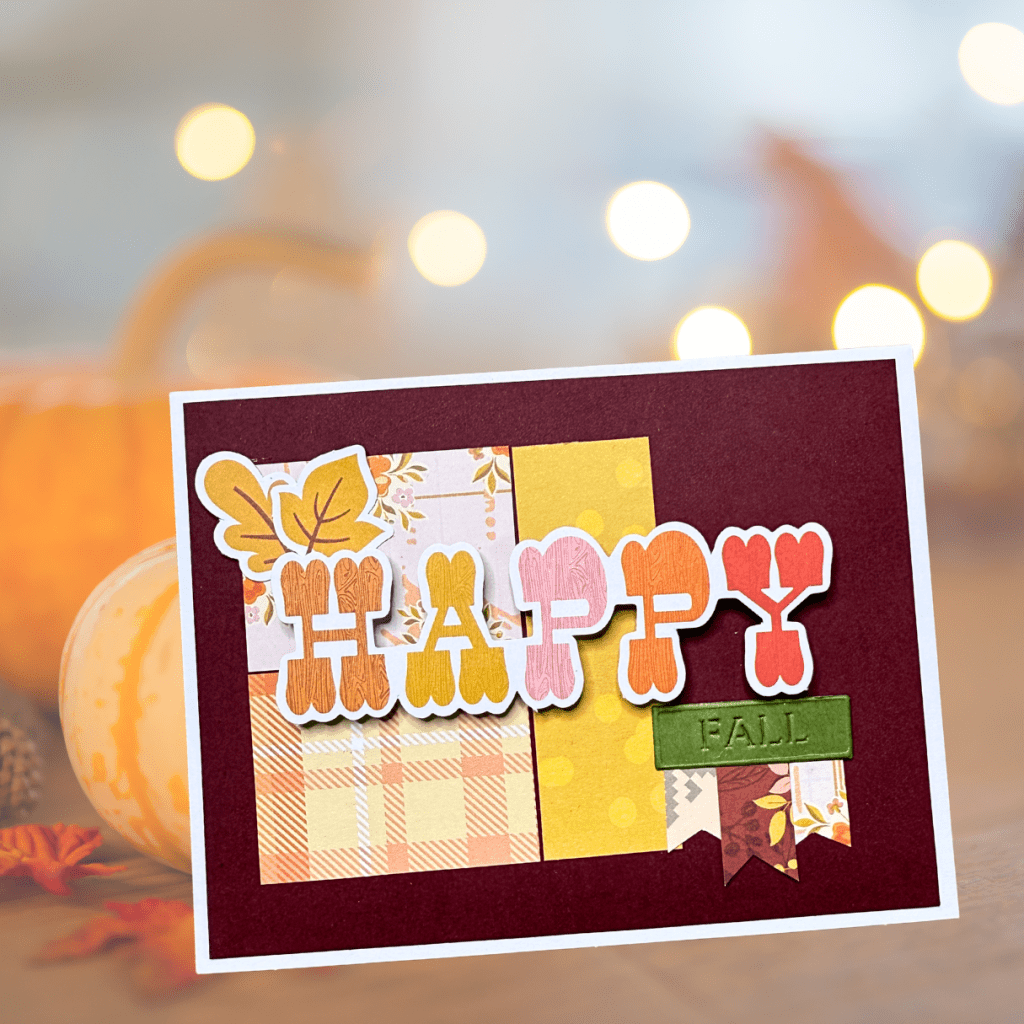 A colorful autumn-themed card with the word 'HAPPY' prominently featured, surrounded by patterned paper in shades of yellow, orange, and pink, along with decorative elements like leaves and banners.