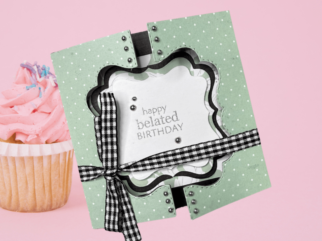 A gate fold card with a polka dot design, featuring the text 'happy belated BIRTHDAY' in the center, embellished with silver gems and a black and white checked ribbon.