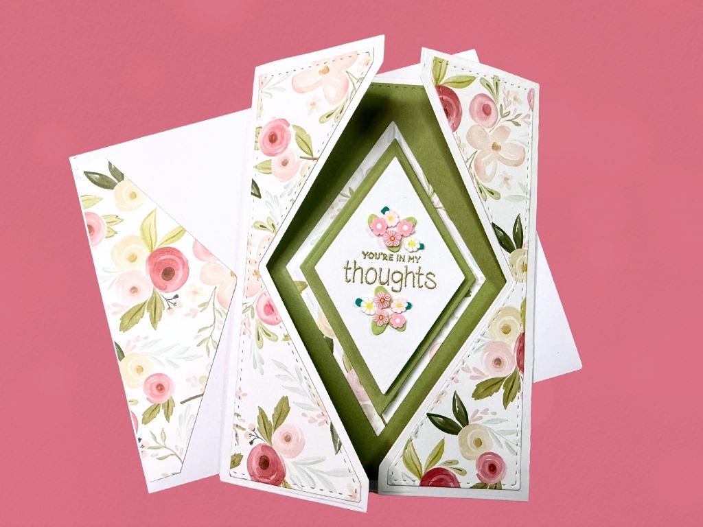A beautifully designed gatefold card featuring floral patterns, with an inner message saying 'YOU'RE IN MY thoughts' embellished with flowers and set against a pastel pink background.