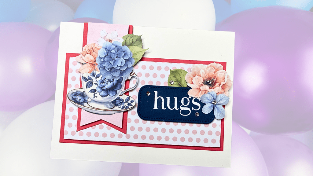 A greeting card featuring a decorated teacup with blue and pink flowers, accompanied by the word 'hugs' on a blue tag, set against a polka dot background and colorful balloons.