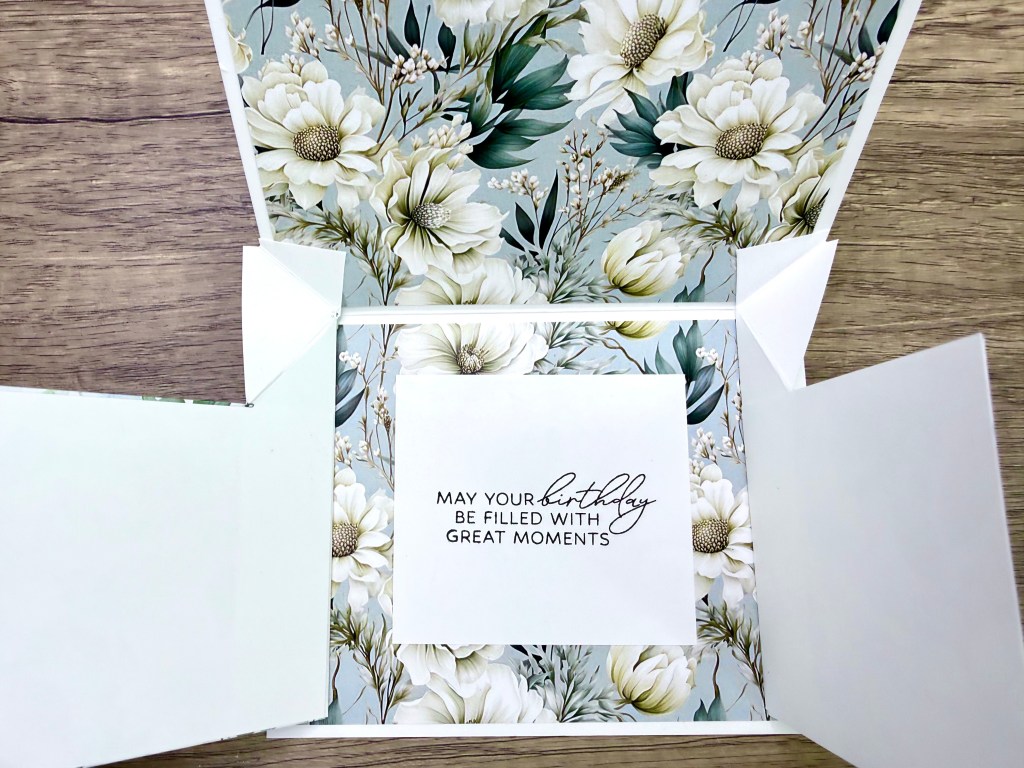 Interior view of a pop-up birthday card featuring floral patterns and a heartfelt message that reads 'MAY YOUR BIRTHDAY BE FILLED WITH GREAT MOMENTS.'