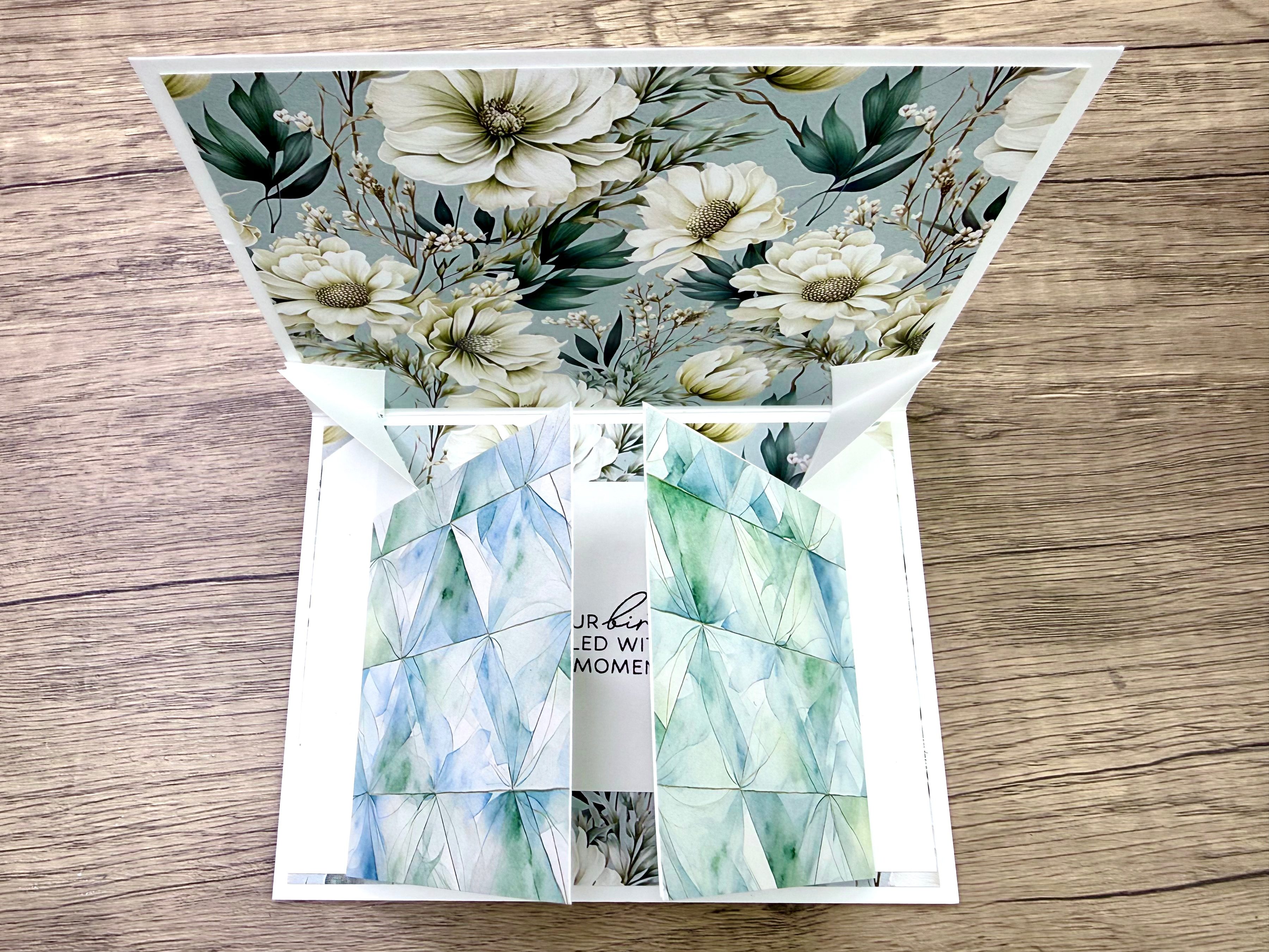 A beautifully designed pop-up card featuring floral patterns in soft colors, with geometric patterns in green and blue inside, showcasing an interactive element.