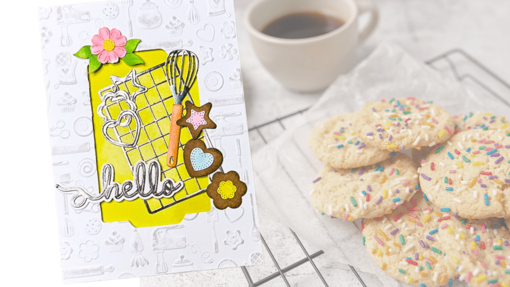 A greeting card featuring a whisk, cookie cutters, and decorative elements on a white background, with the word 'hello' in a stylish font, alongside a plate of colorful sprinkle cookies and a cup of coffee.