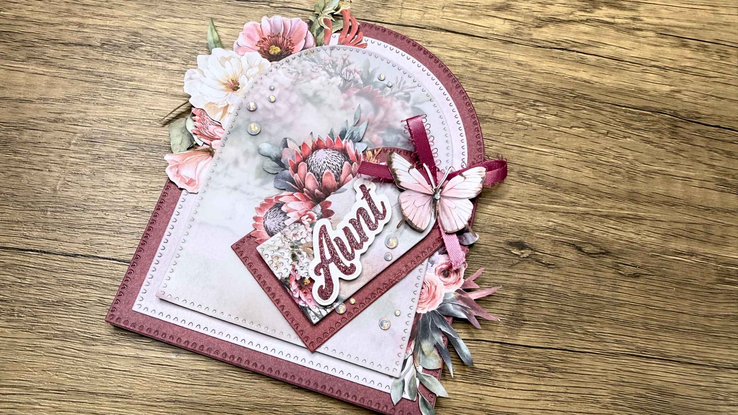 3 Handmade floral card with the word 'Aunt' and a pink butterfly decoration on wooden surface