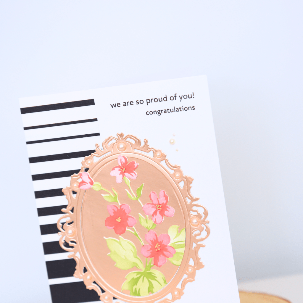 Card with black and white stripes, rose gold floral frame, and text reading 'we are so proud of you! congratulations'