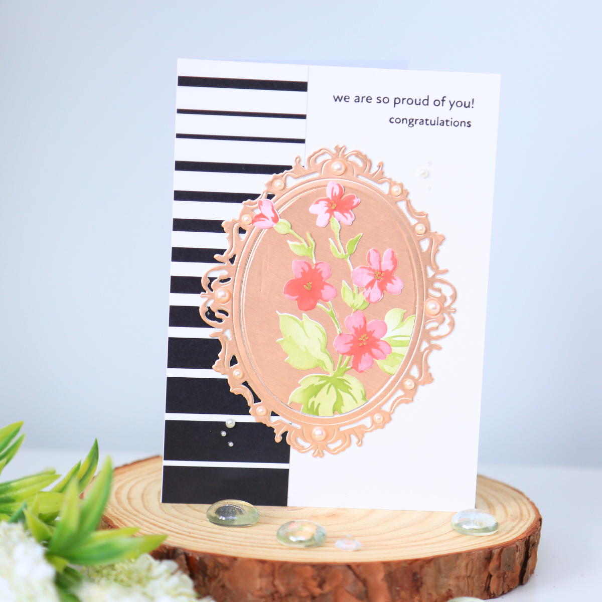 HandmadeCardsByToni-EnchantedBeginnings-HillBlossoms-6 Card with black and white stripes, rose gold floral frame, and text reading 'we are so proud of you! congratulations'
