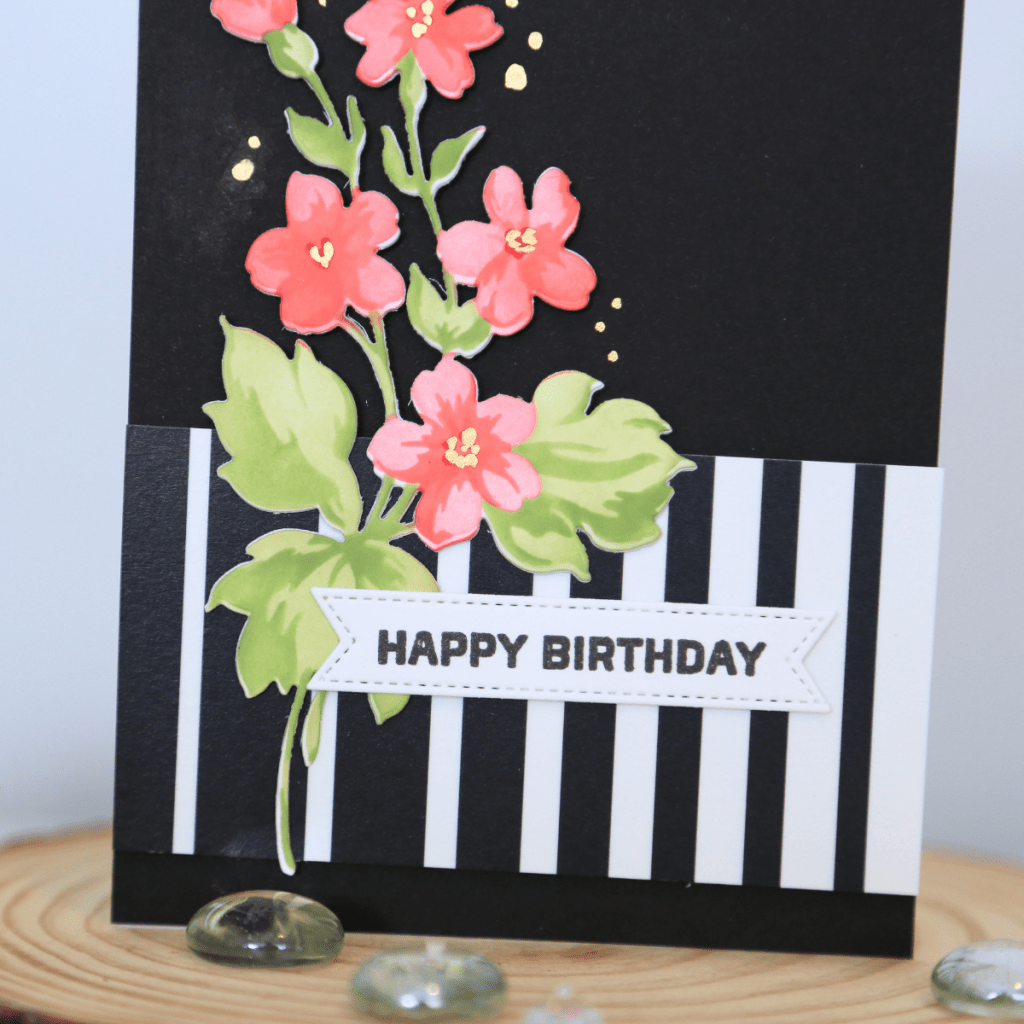 Happy birthday card with pink flowers and green leaves on black and white striped background