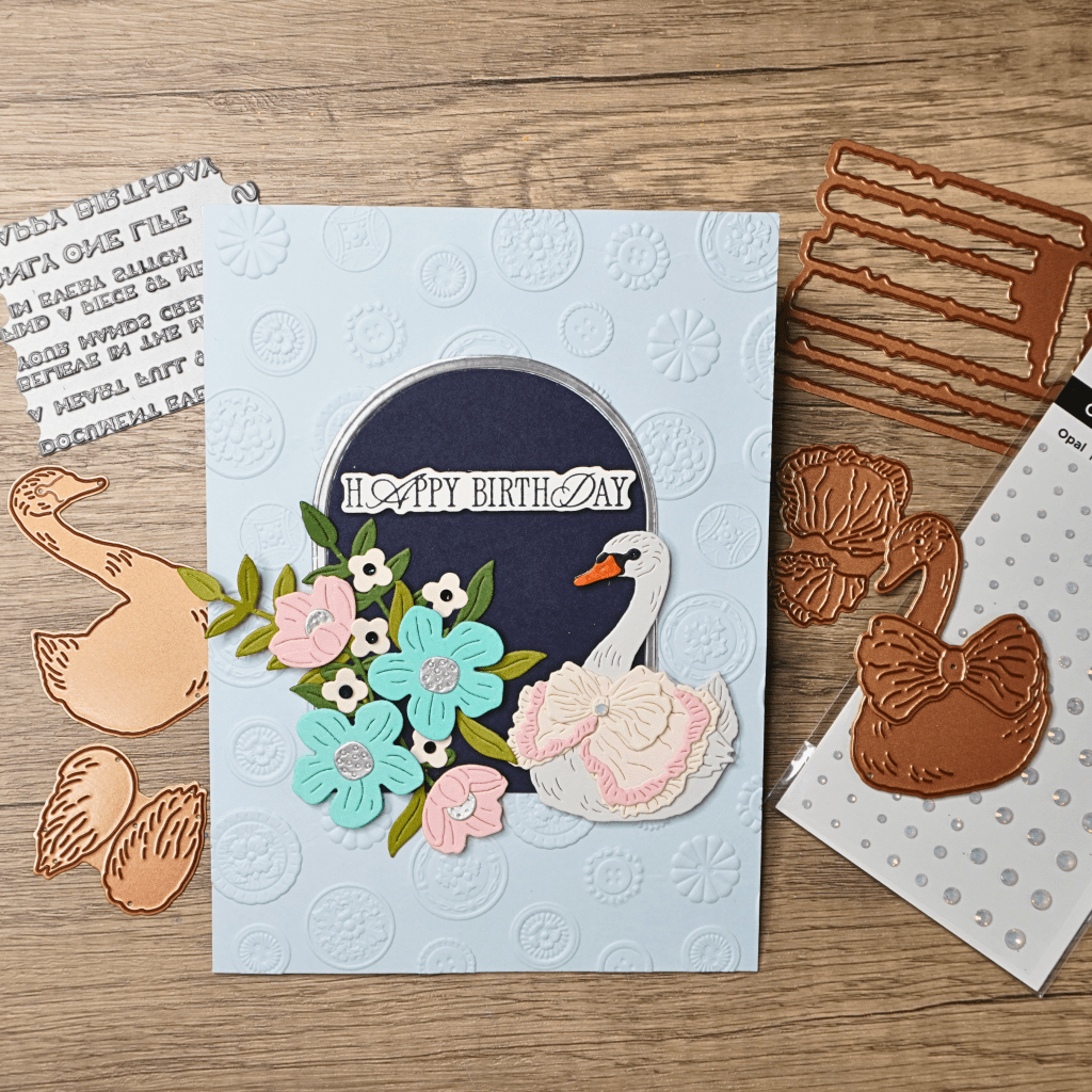 Elegant handmade birthday card featuring a swan surrounded by flowers inside an arched frame.